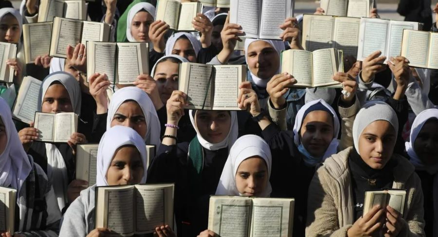 مسلمان باحجاب لڑکیاں قرآن مجید ہاتھوں میں اٹھائے ہوئے مظاہرہ کر رہی ہیں